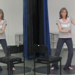 A dancer dances - standing with her legs bent and her arms swaying - she is reflected in the full length mirrors next to her - giving her a partner
