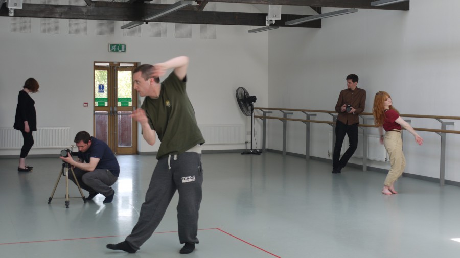 a wide shot of a dance rehearsal. A male dancer is at the front, a female dancer at the back - both have camera men tracking them.