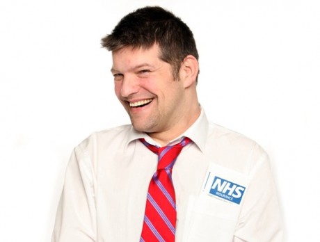 a head and shoulders shot of Laurence Clark - he is in a white shirt and red tie with an NHS badge on. He is smiling cheekily.