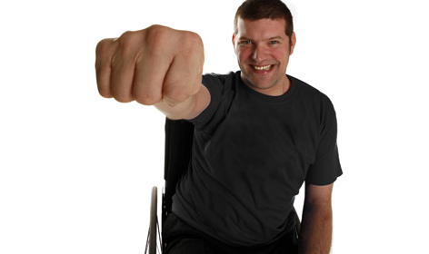 A photo of laurence Clark, is hand and arm raised making a fist towards the camera so his hand appears very big.