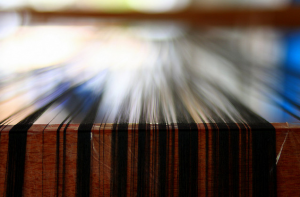 dark threads on a table, ready for weaving